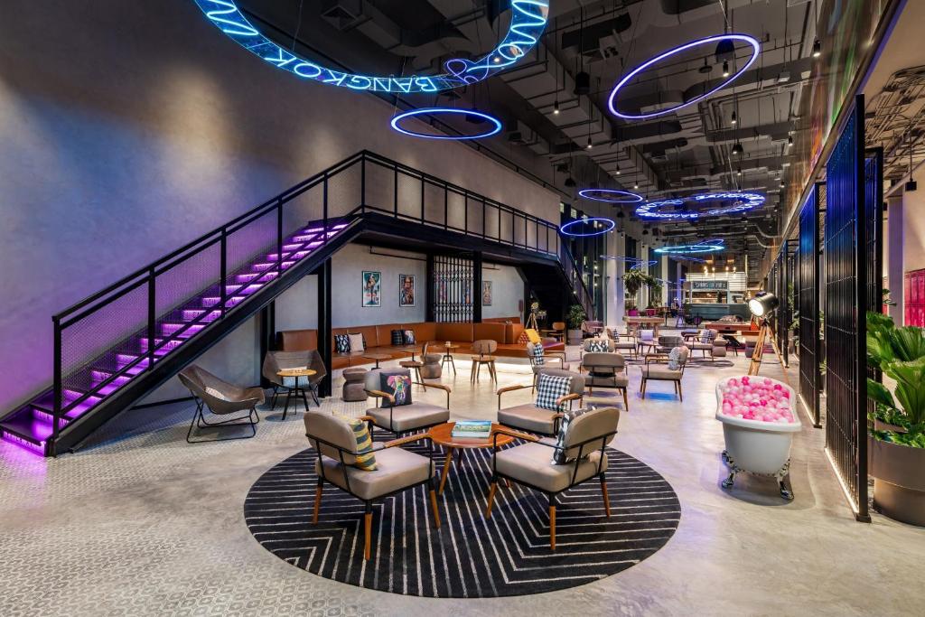 a lobby with a waiting area with chairs and tables at Moxy Bangkok Ratchaprasong in Bangkok