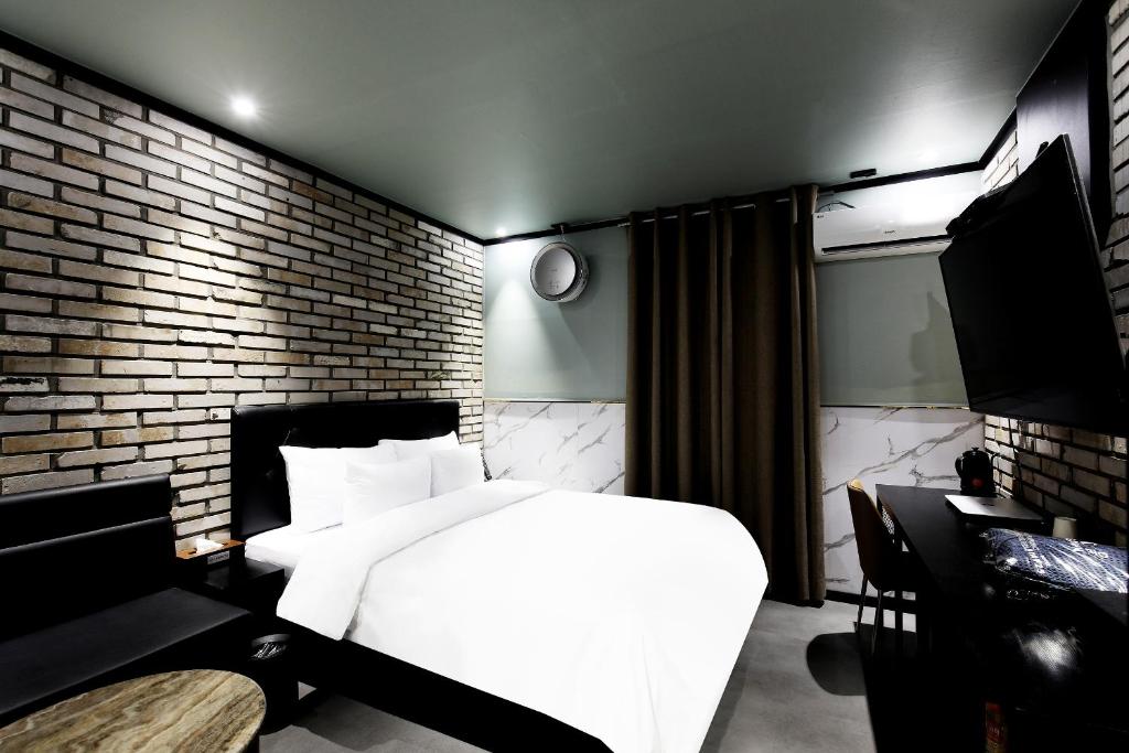 a bedroom with a white bed and a brick wall at Stay 25 Hotel in Seoul