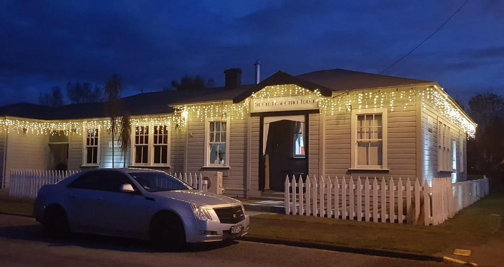 Owhango的住宿－5-Star OLD POST OFFICE HOLIDAY HOME - 5-7-Bedroom Art Deco Elegance，一座遮盖在圣诞灯下的房屋,前面有一辆汽车