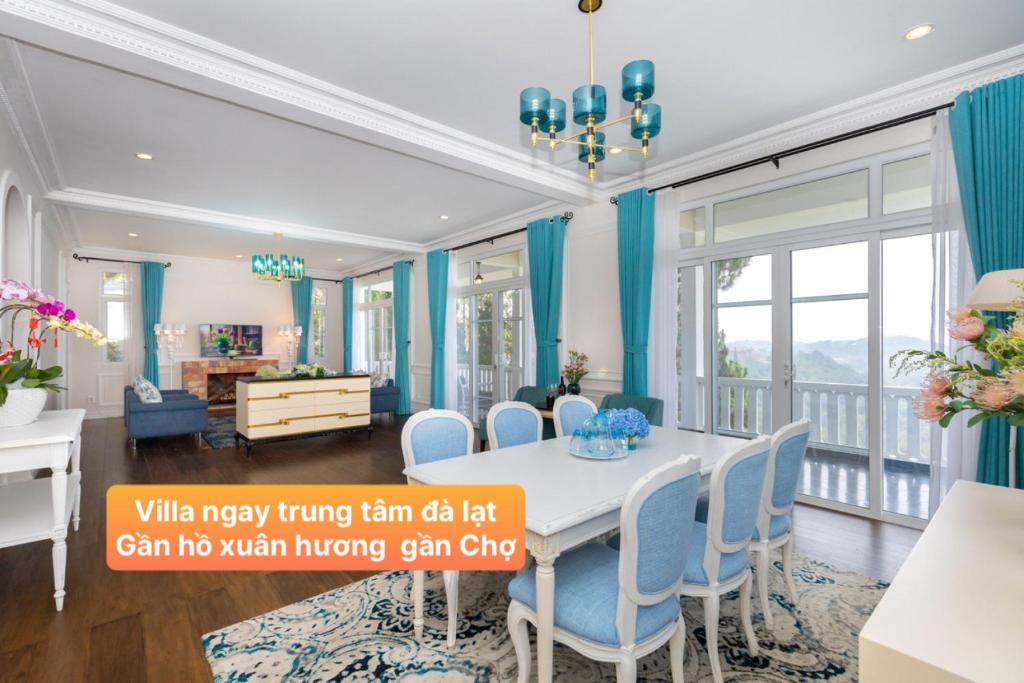 ein Esszimmer mit blauen Vorhängen sowie einem Tisch und Stühlen in der Unterkunft Villa Hạng Sang Đà Lạt - Gần Hồ Xuân Hương Gần Chợ Đà Lạt in Xuan An