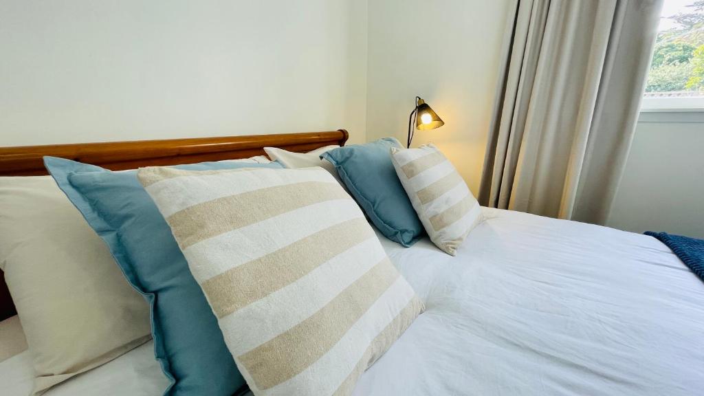 a bed with blue and white pillows and a window at Stay on Glanmire in Wellington