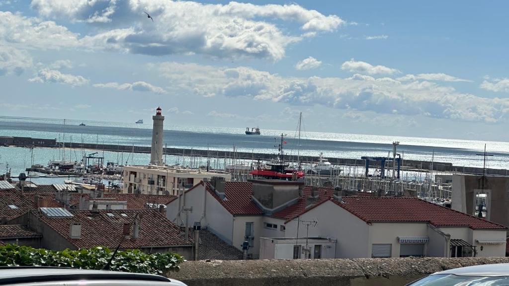 une vue d'une plage avec un phare et des bâtiments dans l'établissement CARPE DIEM, à Sète