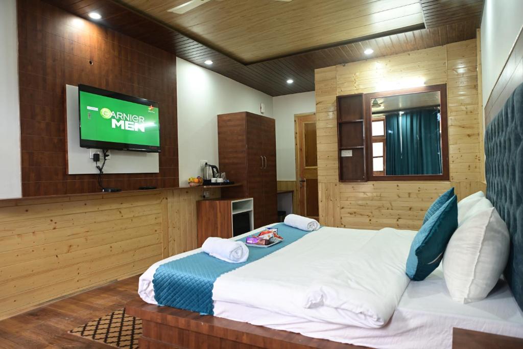 sypialnia z łóżkiem z telewizorem na ścianie w obiekcie Nirvana -A Balcony Rooms Hotel-A True View Of Mountains w mieście Manāli