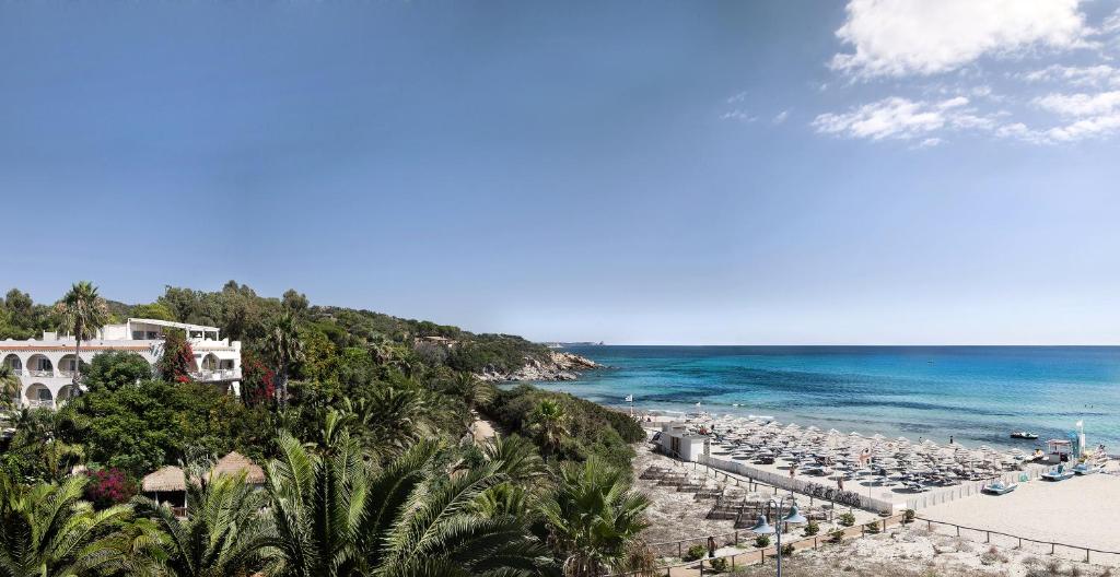 a beach with a bunch of umbrellas and the ocean at Hotel Simius Playa in Villasimius