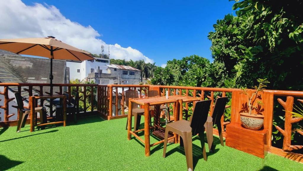 una terraza de madera con mesa, sillas y sombrilla en CiNta Hotel en Boracay