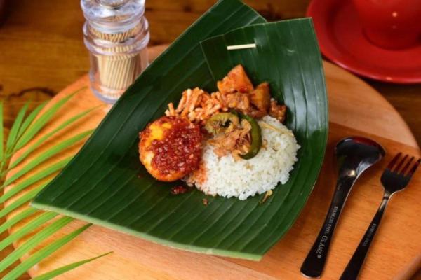 um prato verde de comida numa mesa com arroz em stay KULTURA em Banda Aceh