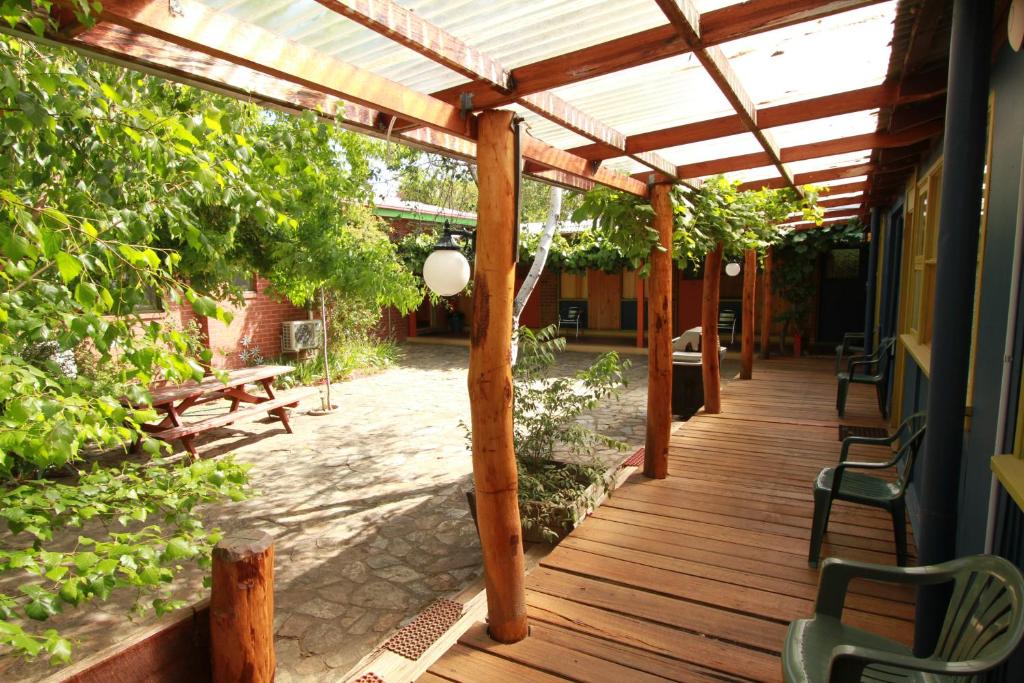 a wooden porch with a pergola and benches on it at Bunkhouse Motel in Cooma