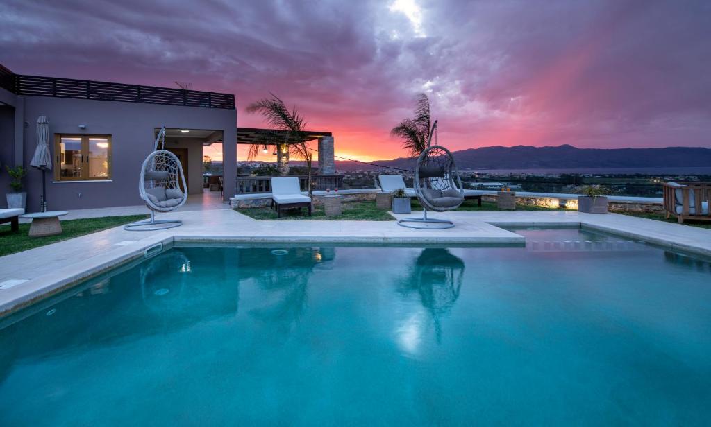 マレメにあるVilla Lady Dafni with private heated poolのスイミングプール(椅子2脚付)と夕日を提供しています。