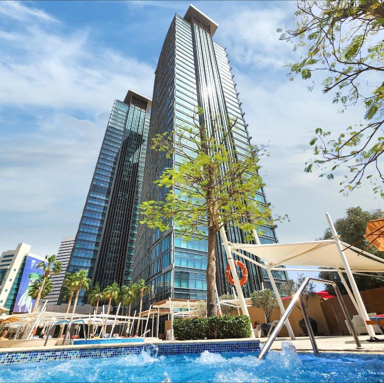 a pool in front of a tall building at City Centre Rotana Doha in Doha