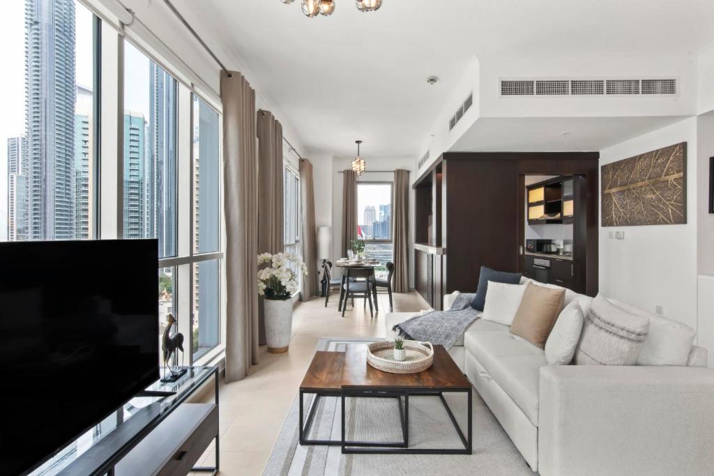 a living room with a couch and a tv at Stunning 1-Bedroom Apartment with full Burj Khalifa View - 5-min walk to Dubai Mall in Dubai