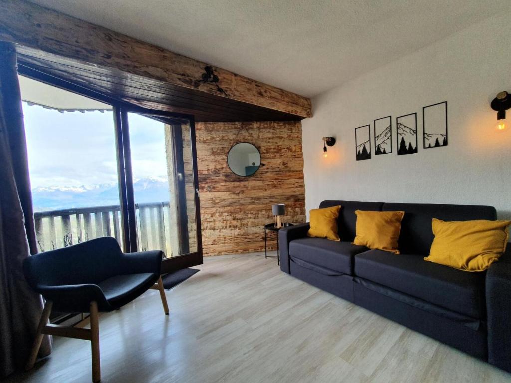 a living room with a couch and a large window at Résidence Les Carlines - Studio pour 4 Personnes 664 in Les Orres