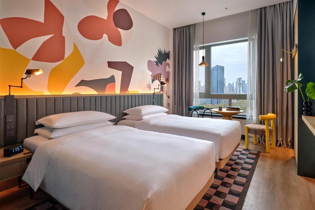 2 łóżka w pokoju hotelowym z oknem w obiekcie Caption by Hyatt Zhongshan Park Shanghai w Szanghaju