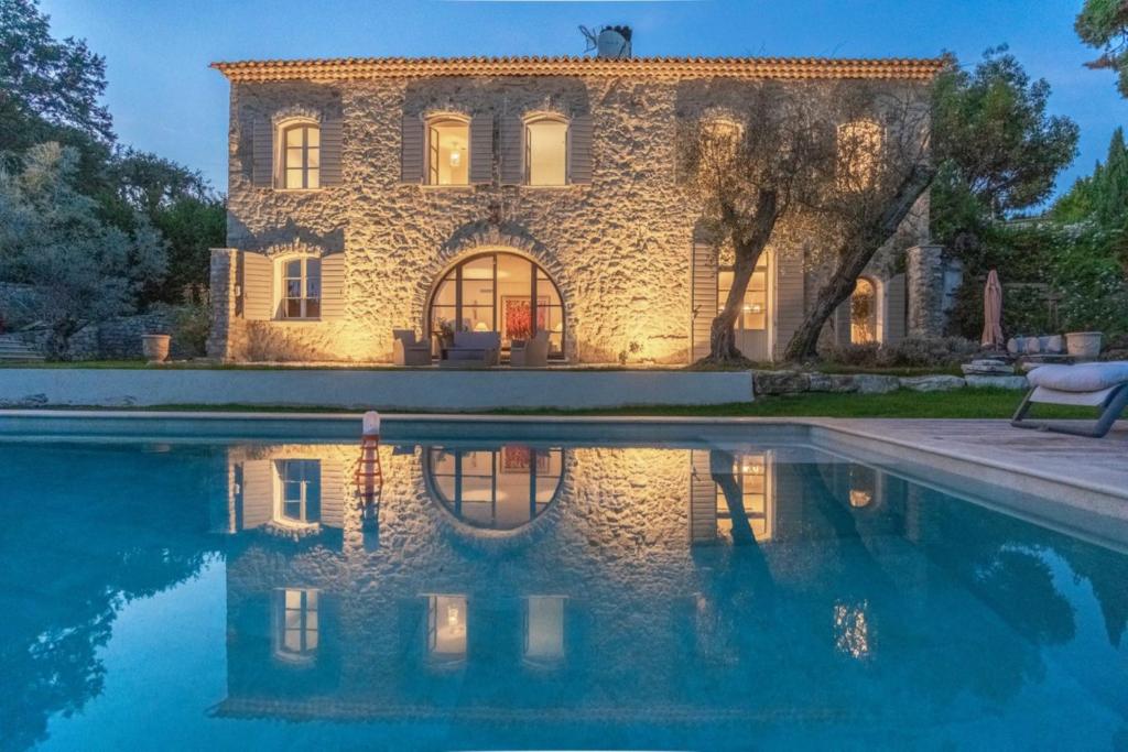 ein Steinhaus mit einem Pool davor in der Unterkunft L'élégante Bastide en pierre avec vue sur le vieux village de Mougins in Mougins