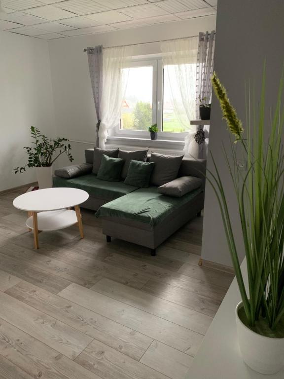 uma sala de estar com um sofá verde e uma mesa em Agroturystyka Pod Dzwonnicą em Zubrzyca Górna