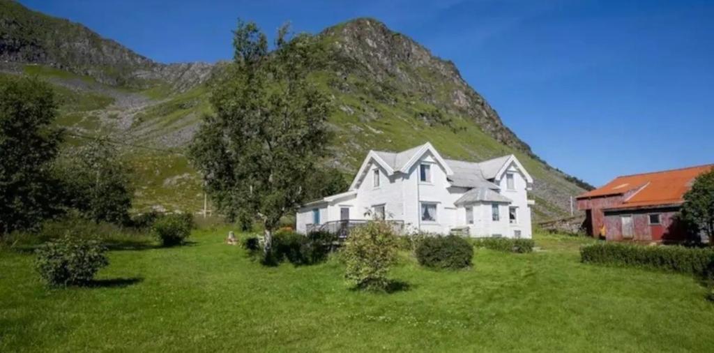 uma casa branca num campo com uma montanha em Mor's hus em Valle