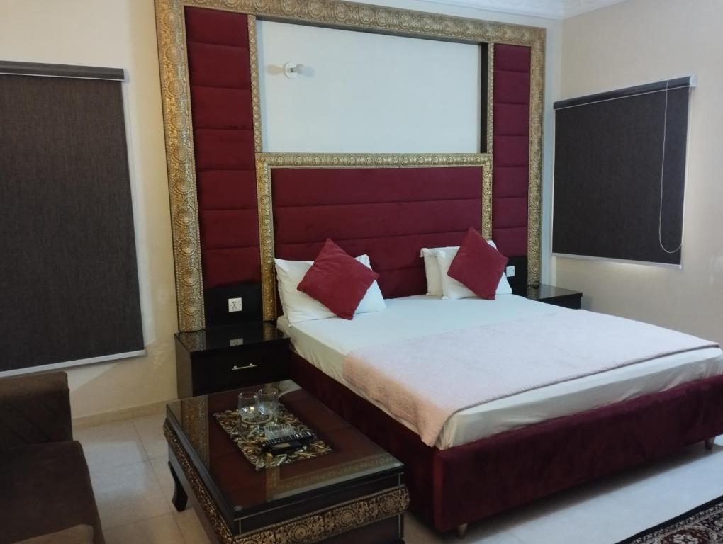 a bedroom with a bed with a red headboard at Hotel Shelton in Karachi