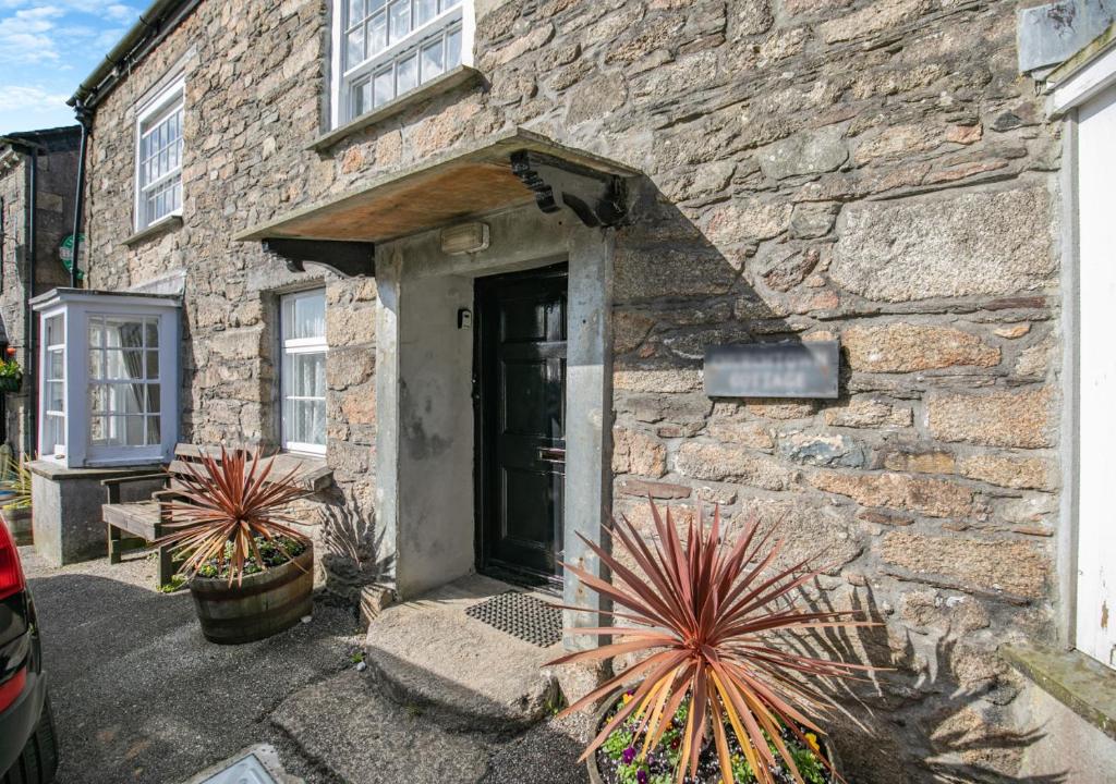 a stone building with a door and plants in front at Churchtown Cottage in Blisland
