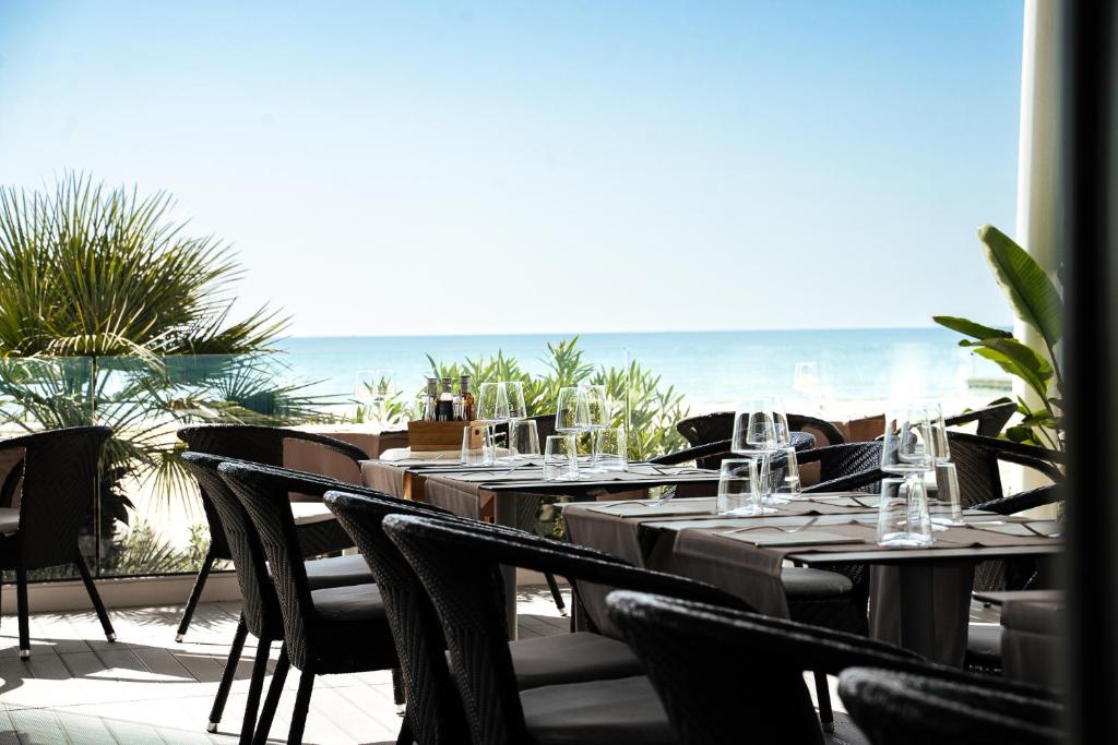 ein Restaurant mit Tischen und Stühlen mit Meerblick im Hintergrund in der Unterkunft Hotel Niagara in Lido di Jesolo