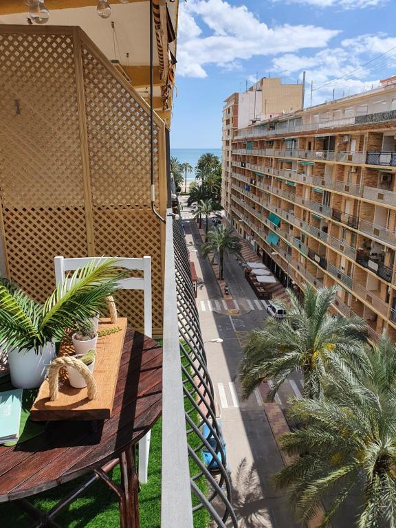 a balcony with a table and palm trees and a building at apartamento playa surf cullera in Cullera