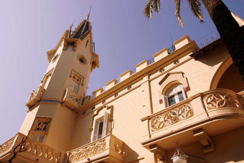 un edificio con torre dell'orologio e balcone di Hotel El Xalet a Sitges