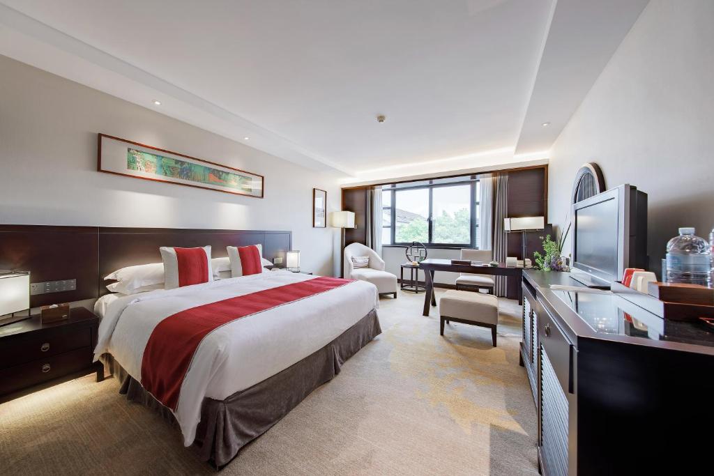 a hotel room with a large bed and a desk at Garden Hotel Suzhou in Suzhou