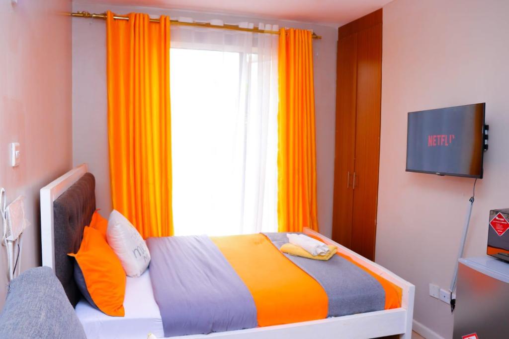 a bedroom with a bed and a window with orange curtains at Comfy Studio Apartment with Pool in Nairobi