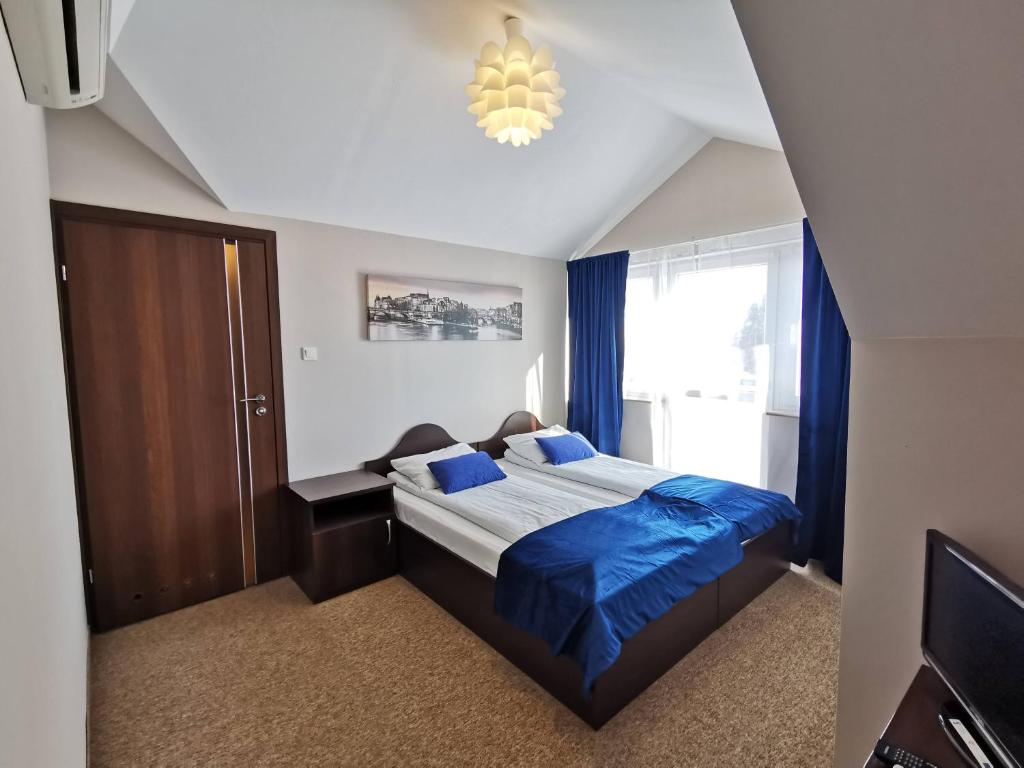 a bedroom with a bed with blue sheets and a chandelier at SAS rooms & restaurant in Długie