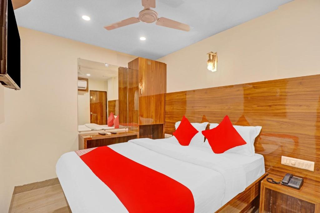 OYO Hotel Royal Park في مومباي: غرفة نوم بسرير كبير ومخدات حمراء