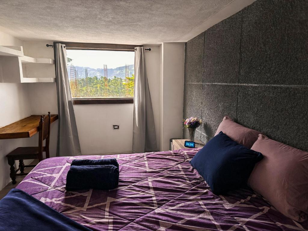 a bedroom with a purple bed with a window at Alta Terra Hospedajes in Quetzaltenango