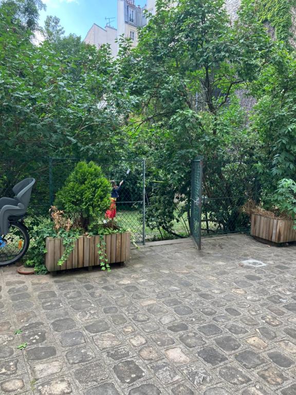un jardin avec une clôture et quelques plantes et arbres dans l'établissement Garden Green, à Paris