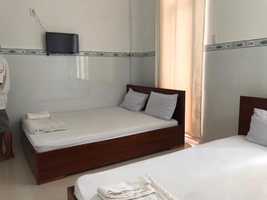 a small room with two beds and a tv at Nam Dương 1 Hotel in Phan Rang