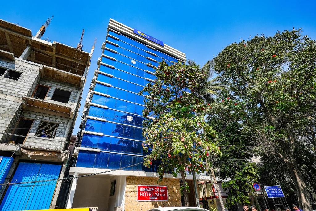 a tall building with blue windows on a city street at FabExpress 24 Plus in Bangalore