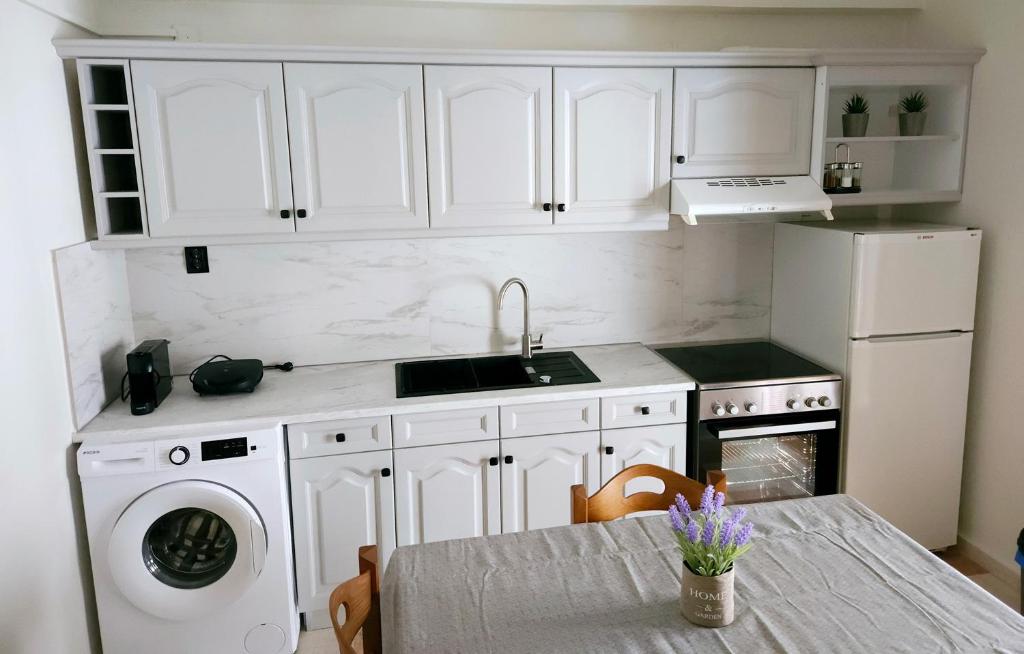 a kitchen with white cabinets and a table with a sink at Paradosi Apartments in Igoumenitsa