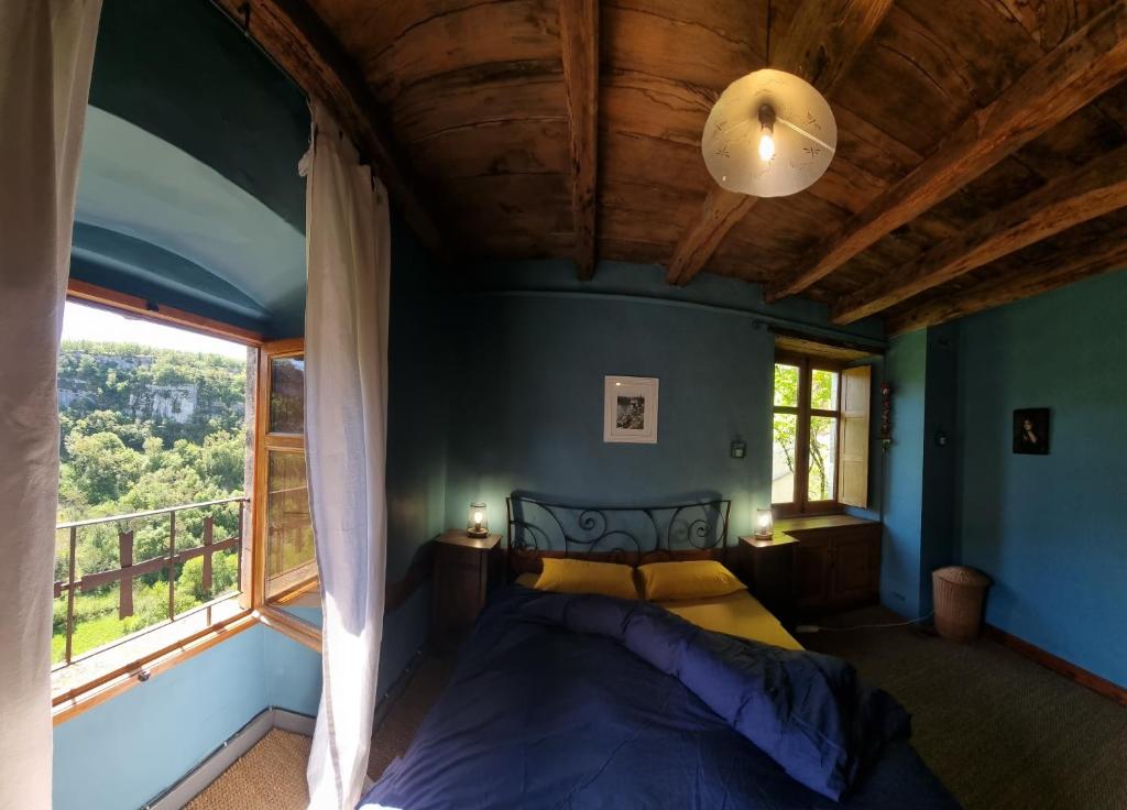 - une chambre avec un lit et une grande fenêtre dans l'établissement l'Ancienne Ecole de Rocamadour dans le Lot, à Rocamadour
