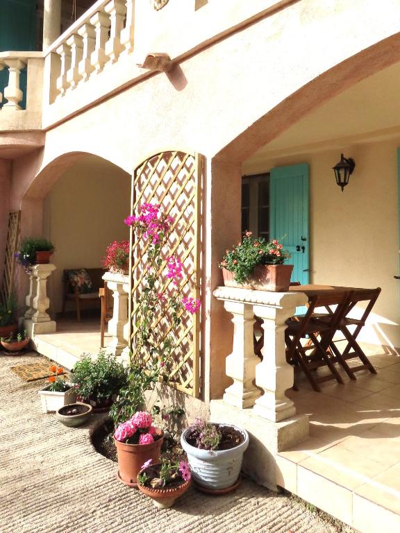 une terrasse avec des plantes en pot, une table et une clôture dans l'établissement La Rose & Le Loup, à Spéracèdes