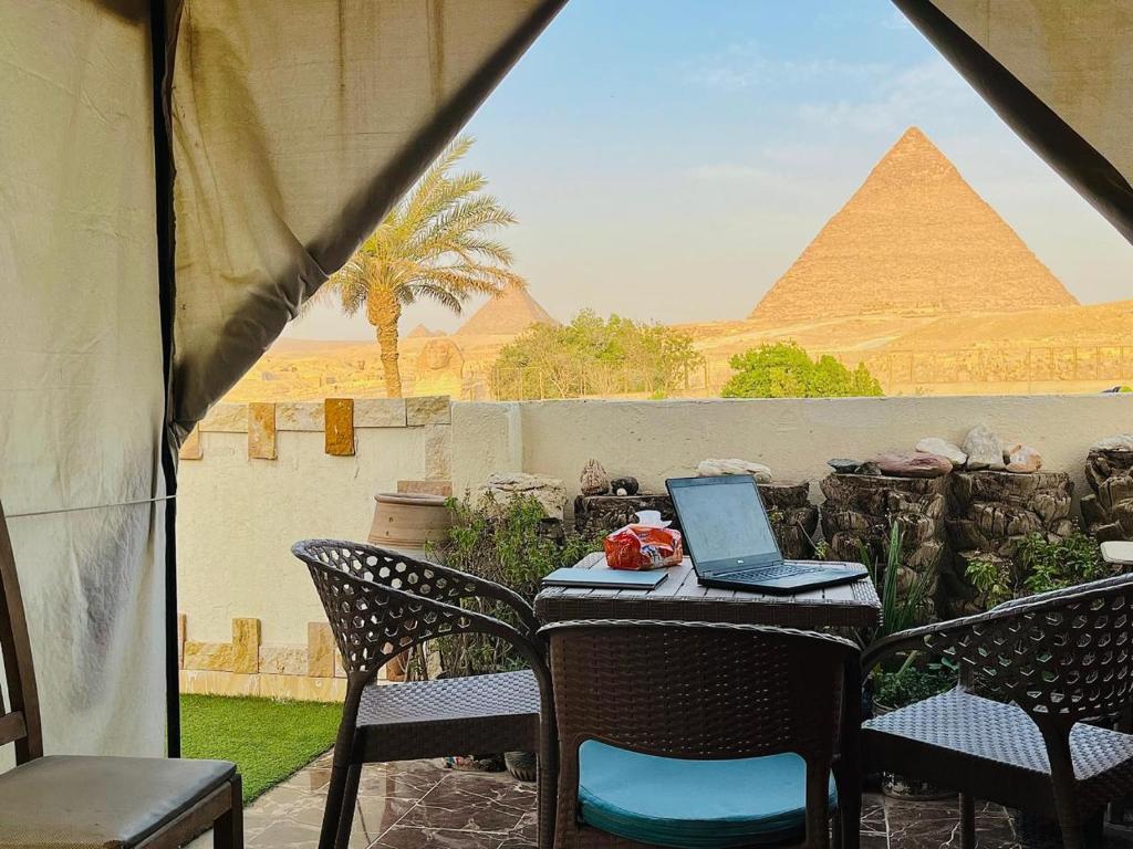 a table with a laptop on it with the pyramid at Kemet Pyramids Room view in Cairo