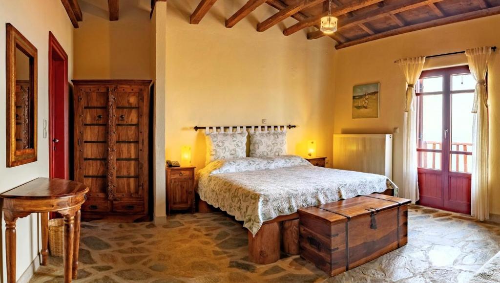 a bedroom with a bed and a wooden dresser at Ethaleia Hotel in Moúdhros