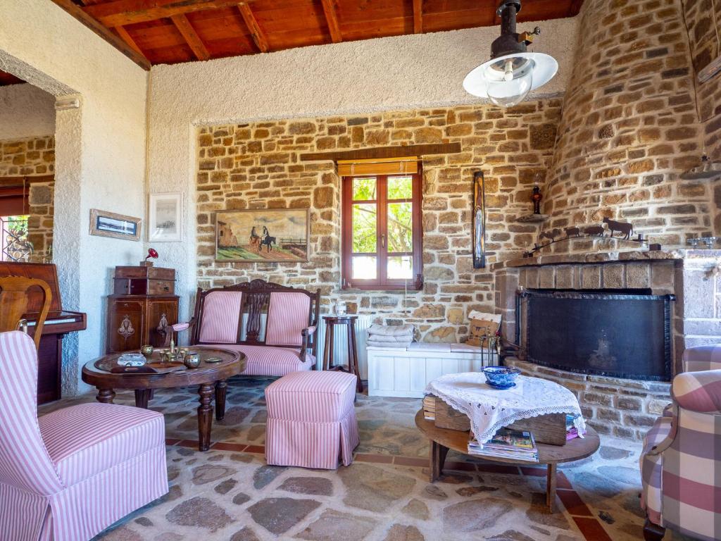 a living room with pink chairs and a stone wall at Ethaleia Hotel in Moúdhros