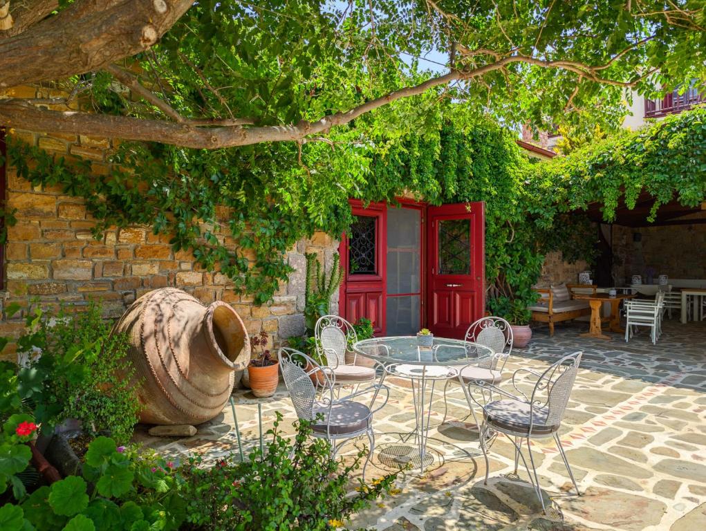 eine Terrasse mit einem Tisch, Stühlen und einer roten Tür in der Unterkunft Ethaleia Hotel in Moúdhros