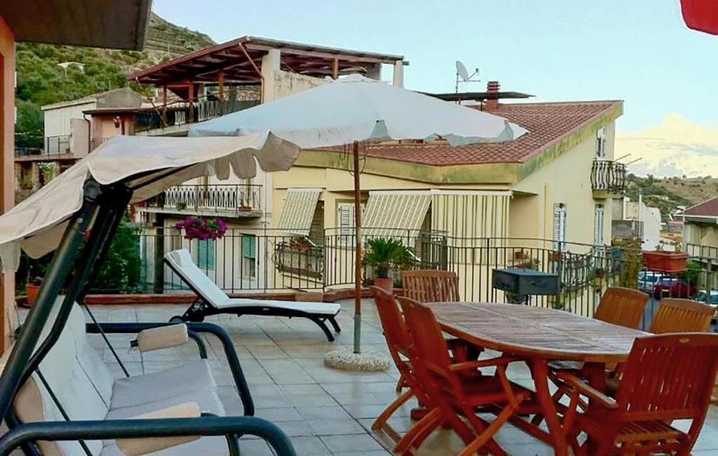 una mesa y sillas con una sombrilla en el patio en Nice Apartment In Furci Siculo With Kitchen, en Furci Siculo
