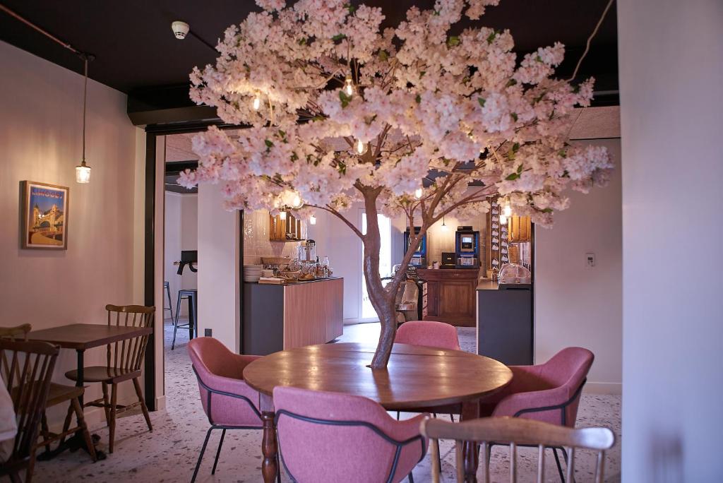 een eetkamer met een tafel en een boom met roze bloemen bij The Originals Access, Hôtel Limoges Nord in Limoges