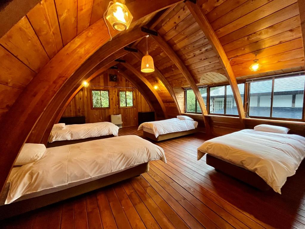 an attic bedroom with three beds in a room at Hakuba Mountain Cabin in Hakuba