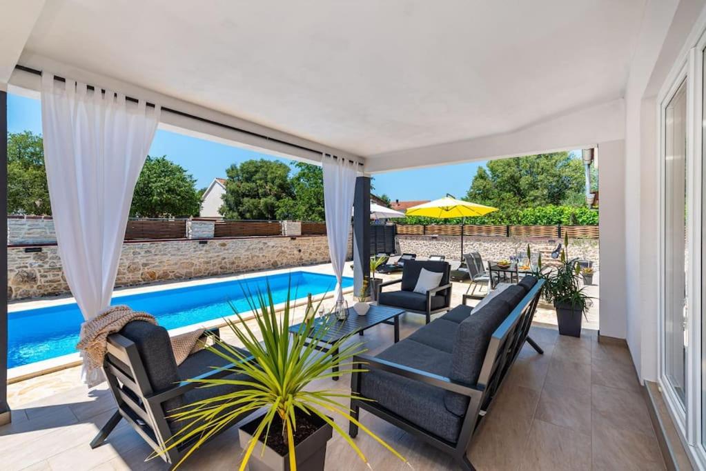 eine Terrasse mit Stühlen und einem Pool in der Unterkunft Villa Lena in Pridraga