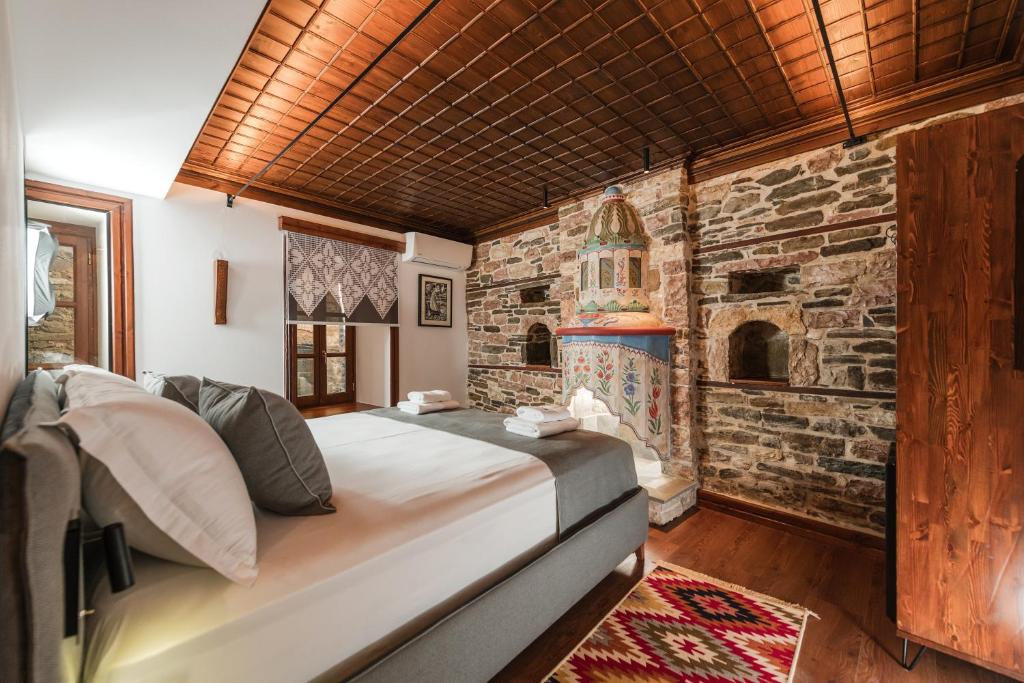 ein Schlafzimmer mit einem Bett und einer Steinmauer in der Unterkunft DAM Stone Boutique Hotel in Gjirokastër