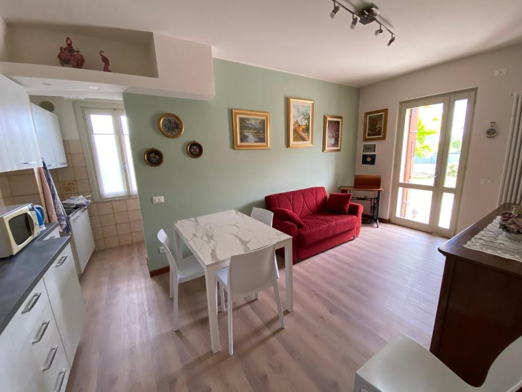 een keuken en een woonkamer met een tafel en een rode bank bij La Corte Di Ottorina in Pederobba
