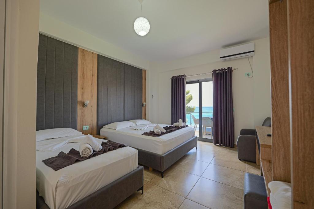 a hotel room with two beds and a balcony at Hotel Esmerald Ksamil in Ksamil