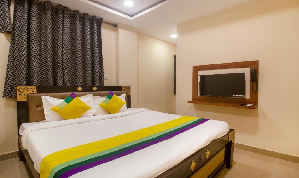 a bedroom with a large bed and a tv at Itsy By Treebo - Yogeshwara Grand in Shamshabad
