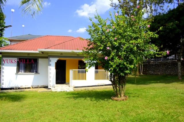 una pequeña casa con un árbol en el patio en Yuks Villa en Kisumu