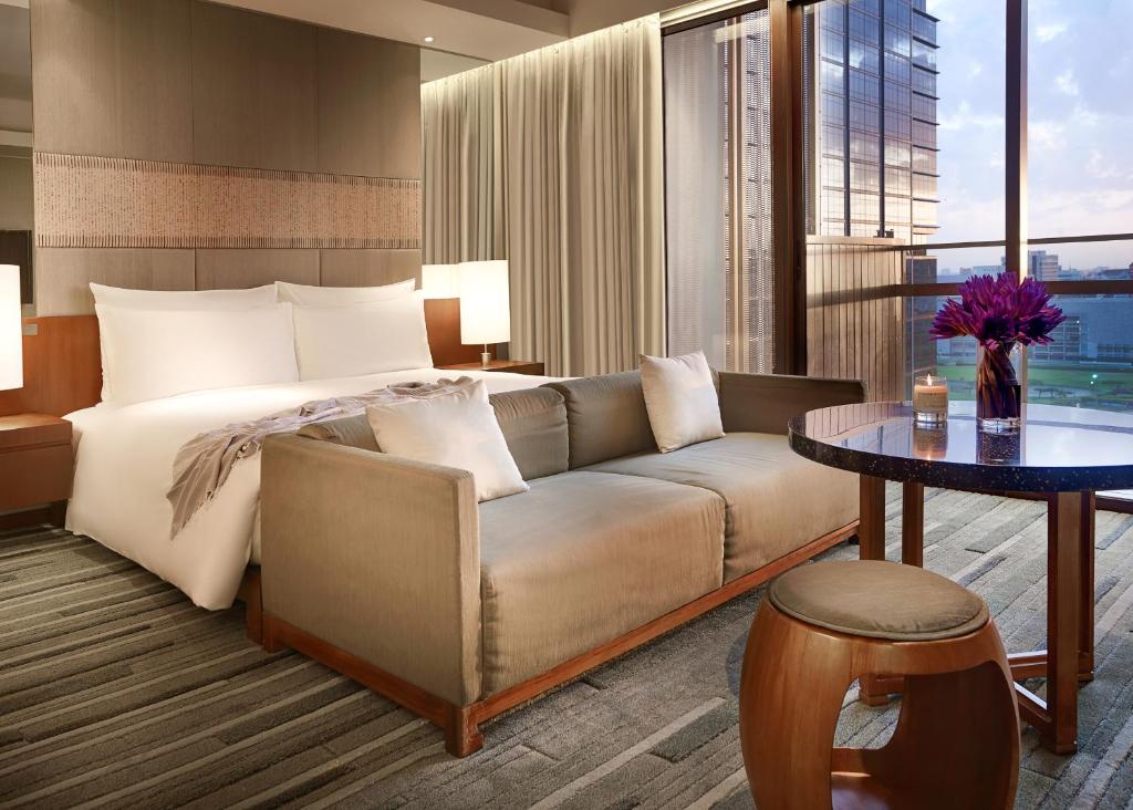 a bedroom with a bed and a couch and a table at Hansar Bangkok Hotel in Bangkok