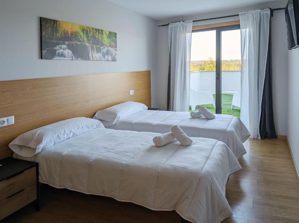 two beds in a hotel room with white sheets at Villa de Arzúa by gaiarooms in Arzúa